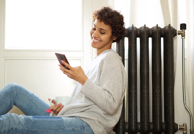 Woman Texting And Drinking Tea, Happy By Radiator